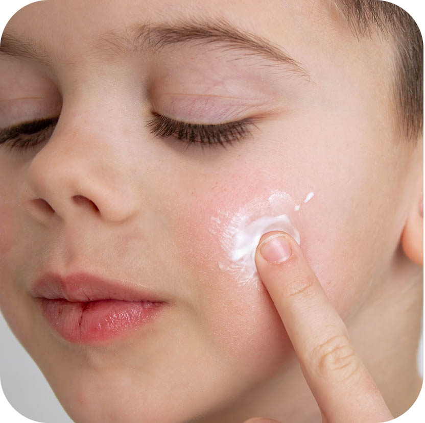 boy applying cream to his face for dry skin.